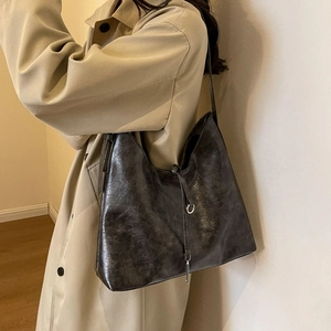 Close-up of a vintage dark grey leather tote bag featuring elegant silver metal rings