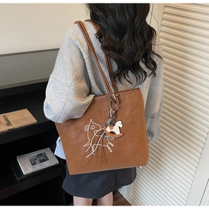 Close-up of brown large tote bag with horse embroidery and rocking horse charm detail