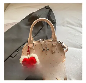 Pink polka dot mini shell bag detail with chain strap and red heart plush charm