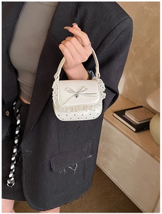 Detailed view of mini white handbag with lace trim, silver bow charm and heart embossed texture