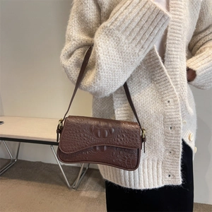 Dettaglio della borsa sottobraccio in pelle marrone scuro con trama a coccodrillo