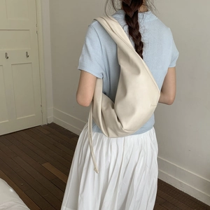 Detail view of cream oversized shoulder bag showing soft leather texture and drape on model