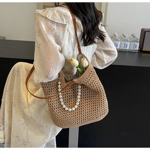 Detailed mesh weave of a straw tote with pearl handle and brown leather strap