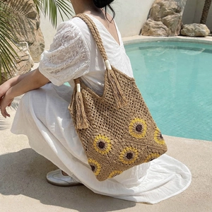 Woven straw handbag with yellow sunflower crochet patterns and tassel for beach vacations
