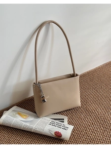 Detail showing smooth light brown matte leather and silver metal chain charm on the shoulder bag