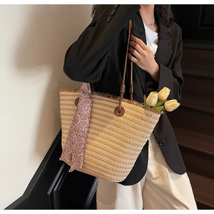 Detail of striped straw tote bag featuring frayed edges, leather handles and silk scarf