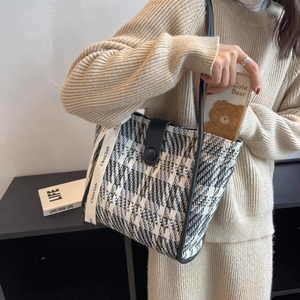 Detail of checkered canvas tote bag with tweed texture, ribbon detail and leather strap