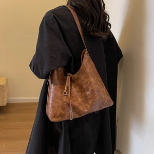 Detail of vintage brown leather tote bag with slim shoulder strap and metallic accents