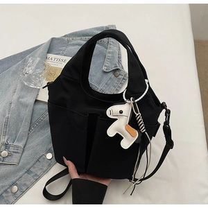 Dettaglio di una borsa tote in nylon nero con tasche funzionali e ciondolo a cavallo