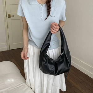 Detailed view of black pleated dumpling shoulder bag with leather texture and metal zipper
