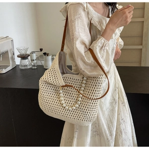 Detail of woven mesh texture on a cream crochet hobo bag with large pearl chain