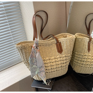 Close-up of woven straw tote bag featuring cutout patterns and floral silk scarf detail