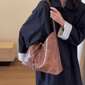 Close-up of vintage brown leather tote bag with silver metal ring and drawstring detail