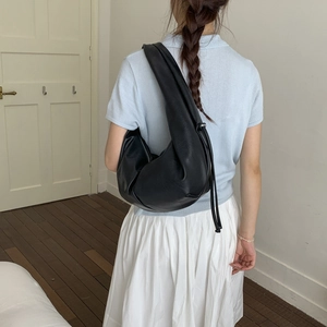 Close-up of a black crescent shoulder bag featuring premium leather texture and drawstring detail