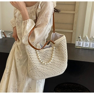 Detailed close-up of beige crochet woven tote bag with brown straps and pearl handle decoration