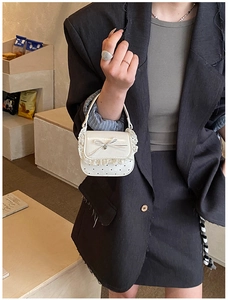 Detailed shot of white mini lace bag with silk bow and heart polka dot pattern