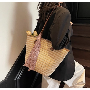 Detail of striped straw tote bag with brown leather handles and a red paisley scarf