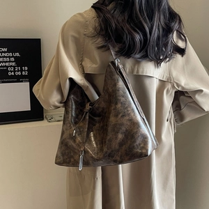 Detail of vintage brown leather tote bag with metallic pendant and textured finish