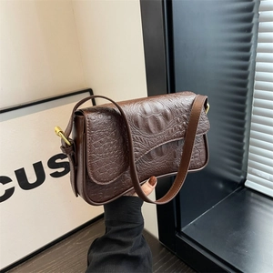 Dettaglio della borsa in pelle marrone con trama coccodrillo e fibbia dorata