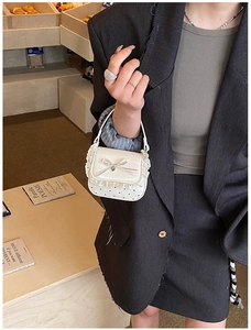 Detail of mini white patent handbag featuring sweet lace trim and a silk bow detail