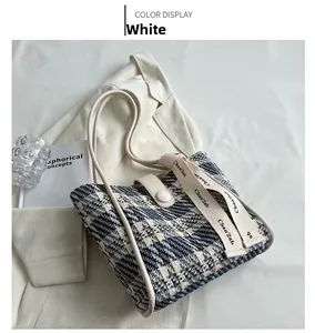 Detail of tweed woven shoulder bag with white leather straps and textured fabric finish