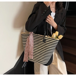 Detail of striped woven tote bag with fringe edge and decorative paisley silk scarf