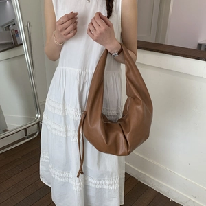 Detail view of caramel brown pleated hobo bag with long drawstring knot shoulder strap