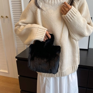 Détail d'un sac seau en fausse fourrure noire douce avec une bandoulière chaîne dorée