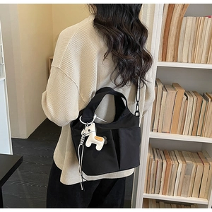 Dettaglio della borsa tote in nylon nero con tasca laterale e ciondolo a forma di cavallo