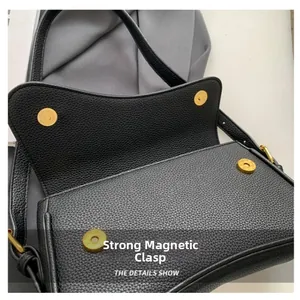 Dettaglio della borsa a tracolla in pelle nera con doppie chiusure magnetiche dorate