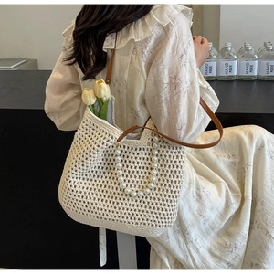 Detail of crochet tote bag featuring elegant pearl handle and leather shoulder strap