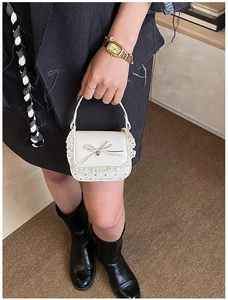 Close-up of a white mini handbag featuring delicate lace edges and a stylish bow detail