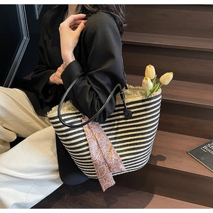 Detailed macro view of black and white striped straw tote bag with brown paisley silk scarf