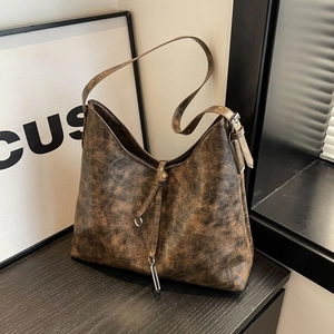 Macro detail of dark brown retro hobo bag showing marble texture and metal ring buckle