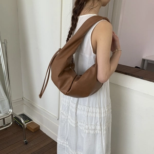 Detail view of brown leather croissant shoulder bag showing side profile on model