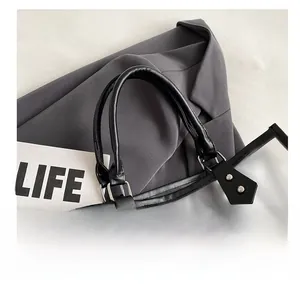 Detail of transparent PVC tote bag with black leather handles and silver metal rivets