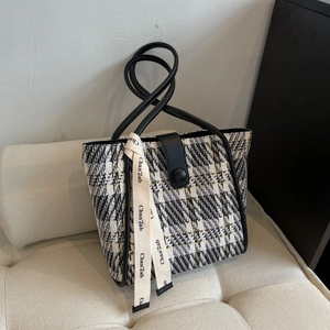 Close-up of the black and white tweed tote bag with leather straps and decorative ribbon