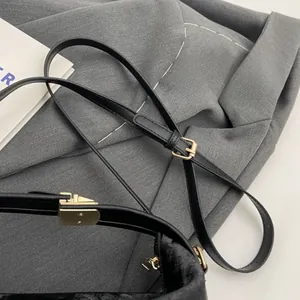 Detail of adjustable black PU leather shoulder strap with golden metal buckle hardware
