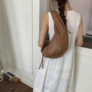 Brown soft leather crescent shoulder bag styled on a model for a minimal office look
