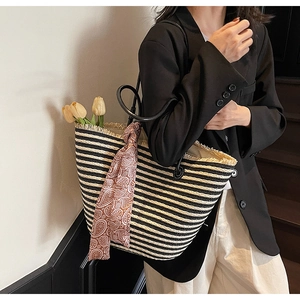 Detail of striped straw tote bag featuring frayed edges and red paisley silk scarf decoration