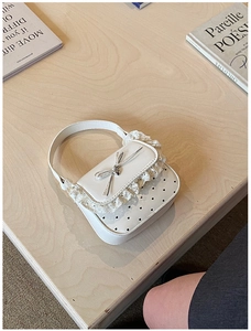 Close-up of white lace trim, silver bow and hollow heart patterns on mini handbag