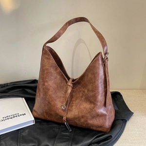 Detail of vintage brown hobo bag showing distressed texture and metal ring buckle