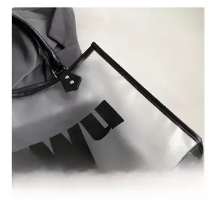 Detail of transparent black PVC tote bag showing silver rivets and DWU lettering