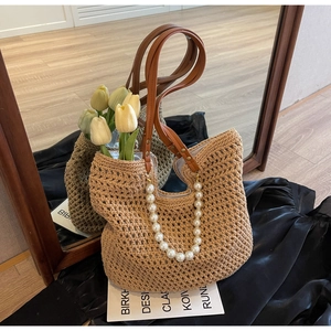 Detailed close-up of handmade straw tote bag with pearl chain and leather handles