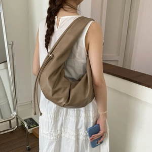 Detail view of the drawstring side on a khaki leather dumpling shoulder bag for women