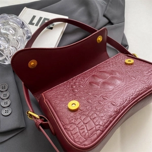 Dettaglio borsa rosso vino scuro stampa coccodrillo con fibbie magnetiche dorate
