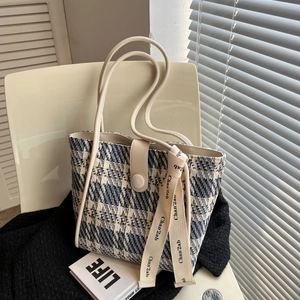 Close-up of blue and yellow tweed tote bag featuring leather handles and decorative ribbon