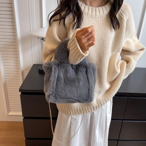 Sac à main en fausse fourrure grise avec chaîne dorée porté par un mannequin en intérieur