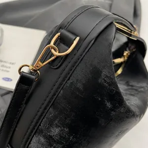 Detailed close-up of golden metal hardware and textured black leather on a small square bag