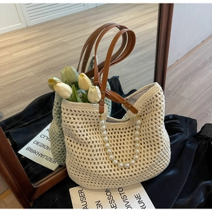 Close-up of woven straw tote bag with honeycomb pattern and pearl chain detail